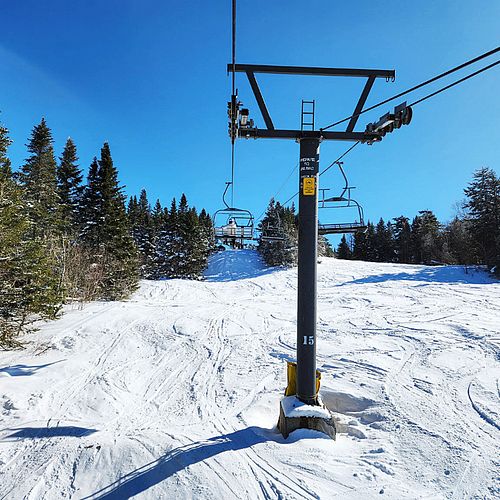 Fresh snow and blue sky seen from a quad chairlift