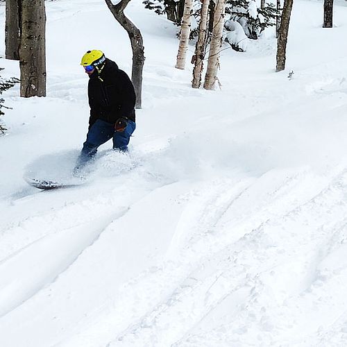 A snowboarder plows through some snow